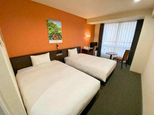 a hotel room with two beds and a desk at Hotel Continental Fuchu in Fuchu