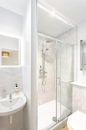a white bathroom with a shower and a sink at North Devon Resort One bedroom sea view hot tub Residence in Ilfracombe