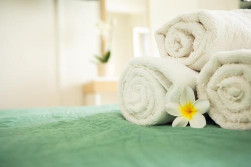 a pile of towels and a flower on a bed at 4YOU STUDIOS in Larnaca