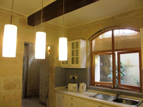 a kitchen with three lights hanging from the ceiling at 19th Century Apartment in Sliema