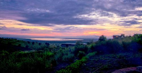 a sunset over a field with a view of the ocean at Wild Tracks Overland Camp in Kasese