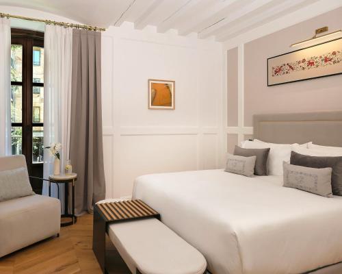 a white bedroom with a large bed and a chair at Eunice Hotel Gastronómico in Salamanca