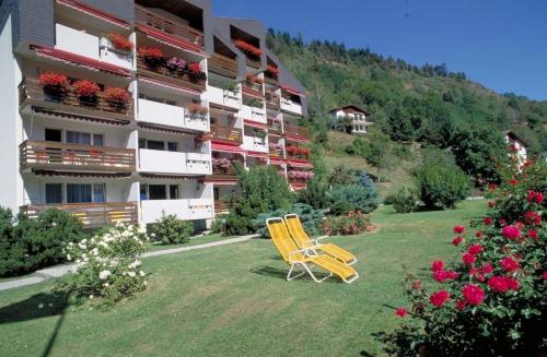 a yellow chair sitting in the grass in front of a building at Serviced Apartments Wallis in Mörel