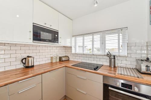 a kitchen with white walls and wooden counter tops at Beach View - East Wittering in Chichester