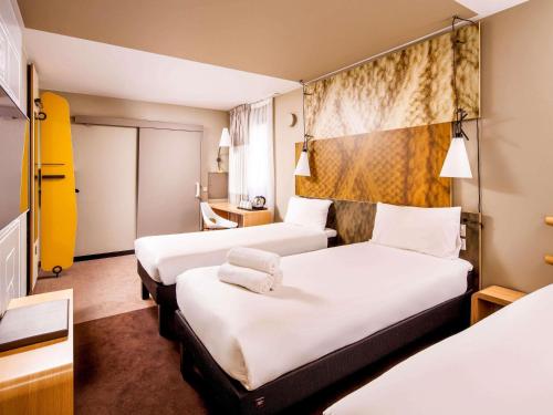 a hotel room with two beds with white sheets at ibis London City - Shoreditch in London