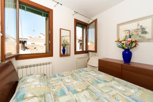 1 dormitorio con 1 cama y un jarrón de flores en Venice Altanina Apartment, en Venecia