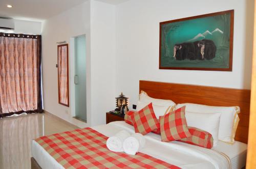 a bedroom with a bed with red and white pillows at Cafe Pinnalanda in Pinnawala