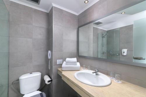 a bathroom with a sink and a toilet and a mirror at Niriides Hotel in Kolymbia