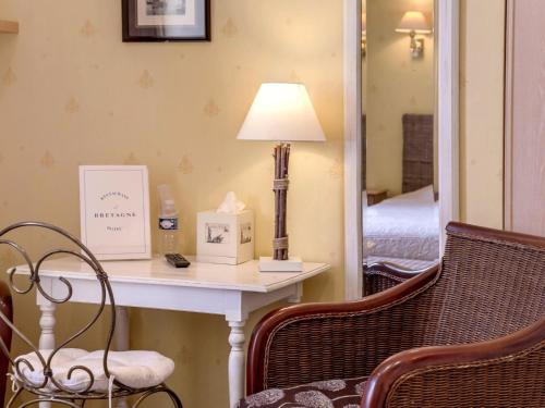 a room with a table with a lamp and a mirror at Logis Le Bretagne in Sillé-le-Guillaume