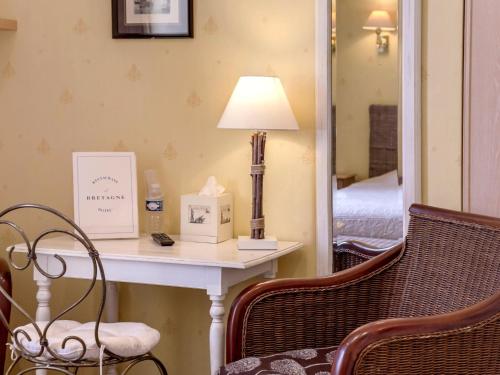 a room with a table with a lamp and a mirror at Logis Hôtel & Restaurant - Le Bretagne in Sillé-le-Guillaume