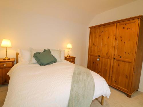 a bedroom with a white bed and a wooden cabinet at Crown Cottage in Belper