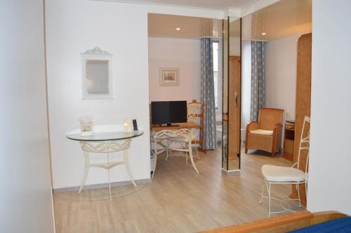 a living room with a table and chairs and a television at Logis Hôtel & Restaurant - Le Bretagne in Sillé-le-Guillaume