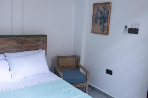 a bedroom with a bed and a chair and a picture at Salasala Suites, Salasala, Mbezi Beach in Dar es Salaam