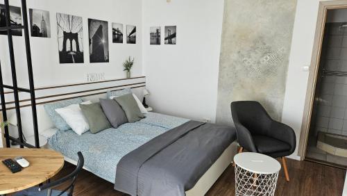 a bedroom with a bed and a chair and a table at Sunlight Apartmanház in Velence