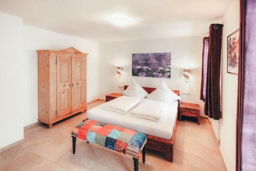 a bedroom with a large white bed and a bench at Luna Blanca - Apartment 2 in Schwangau