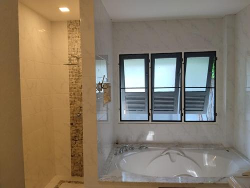 a white bathroom with a tub and a window at Origin life in Ban Na Sat