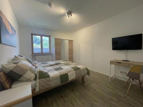 a bedroom with a bed and a desk and a television at Ferienwohnung Bergblick in Marquartstein