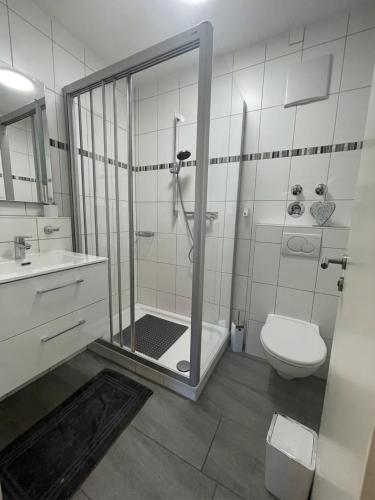 a white bathroom with a shower and a toilet at Ferienwohnung Bergblick in Marquartstein
