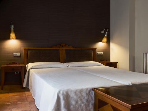 a bedroom with a large white bed and two lights at Hospederia de Loarre in Loarre