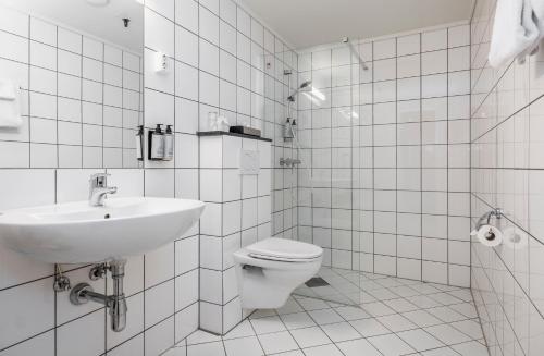 a white bathroom with a toilet and a sink at Thon Hotel Baronen in Ålesund