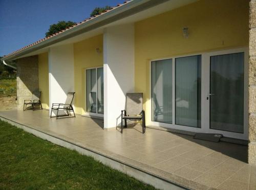 two chairs sitting on a patio next to a house at Agroturismo A Fidalga in Linhares