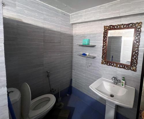 a bathroom with a toilet and a sink and a mirror at Swami Manjulanand Ashram in Mohan Chatti