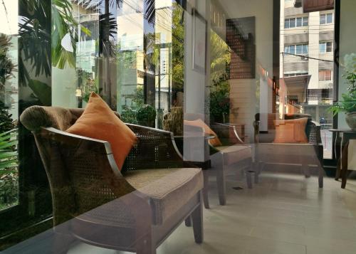 a room with chairs and a window with plants at Mhonsa Hotel in Chiang Mai