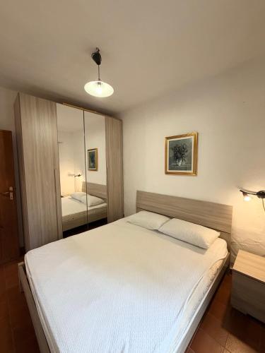 a bedroom with a large white bed and a mirror at Bilocali Ibiscus - 700mt dalla spiaggia in Porto Ottiolu