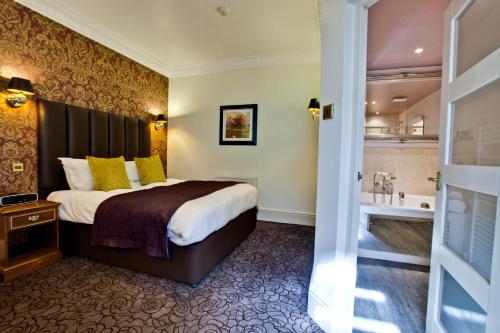 a hotel room with a bed and a bath tub at Pontlands Park Hotel in Chelmsford