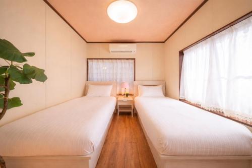 two beds in a room with a window at 絶景貸切別荘in山海荘 無料専用BBQスペースと駐車場付 in Shirahama