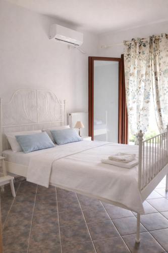 a bedroom with a large white bed with blue pillows at Emma's HOUSE near beach in Tsakaíoi
