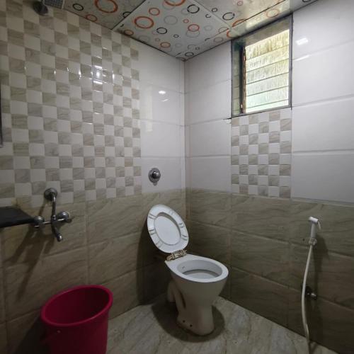 a bathroom with a toilet with a window and a bucket at SIYA International Lodging And Boarding in Bhiwandi