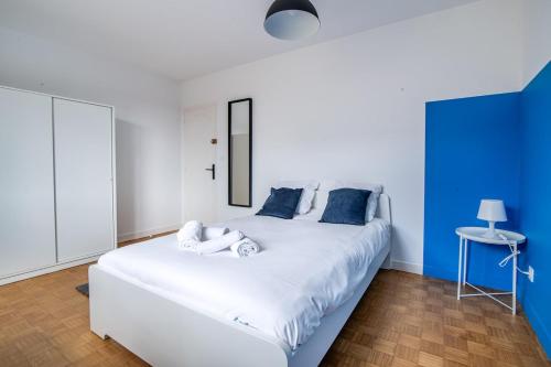 a bedroom with a large white bed with blue walls at L'Echappée Choletaise, simple et familiale! in Cholet