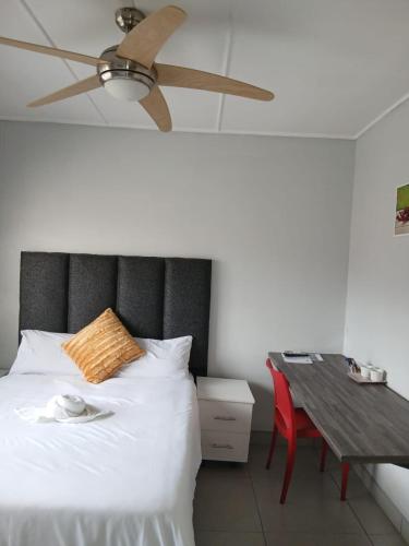 a bedroom with a bed with a ceiling fan and a table at Abebe Guest House in George