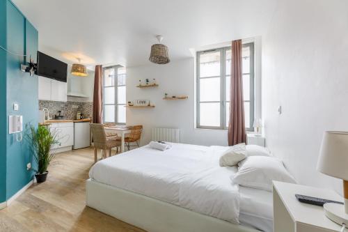 a white bedroom with a bed and a kitchen at Nid Amour Cabane et Spa Privatif in Rouen