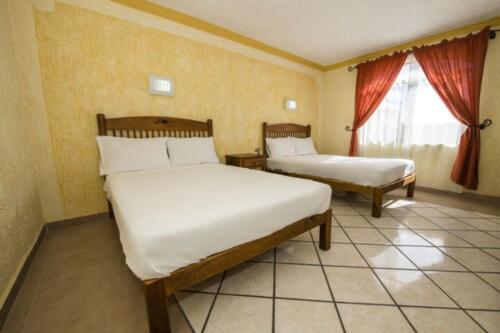 a hotel room with two beds and a window at OYO Hotel La Glorieta, Huichapan in Huichapan