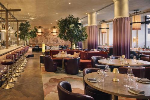 a restaurant with tables and chairs and a bar at The Trafalgar St James London Curio Collection by Hilton in London