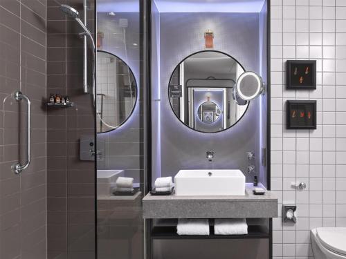 a bathroom with a sink and a shower with a mirror at The Trafalgar St James London Curio Collection by Hilton in London