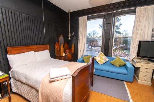 a bedroom with a bed and a couch and a television at Cornerstone Manor Hotel in Sale