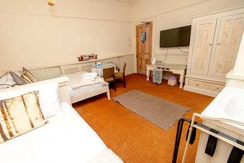a room with a bed and a desk and a television at Cornerstone Manor Hotel in Sale