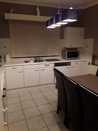 a kitchen with white cabinets and a table with chairs at Wenceslas Cobergher III in Bertem