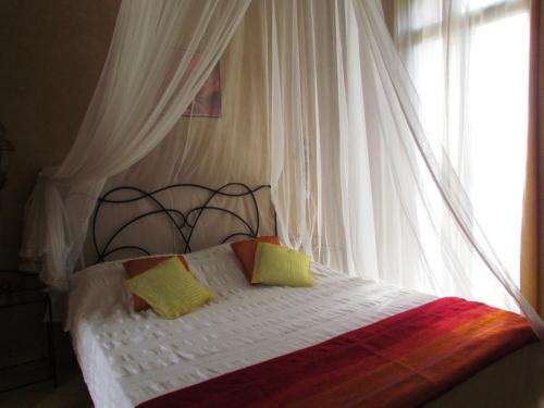 a bedroom with a white canopy bed with two pillows at Le Jardin Des Epices in Taroudant
