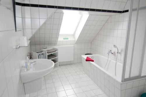 biała łazienka z umywalką i wanną w obiekcie Pension Regina - Inh. Monique Kluge w mieście Gotha