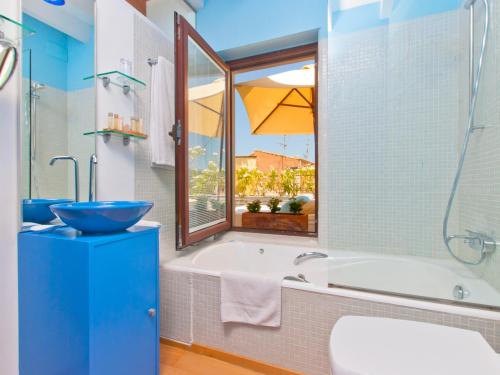 a bathroom with a tub and a sink and a window at Cas Ferrer Nou Hotelet in Alcudia