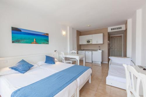 a bedroom with a large bed and a kitchen at Sol de Alcudia Apartamentos in Port d'Alcudia