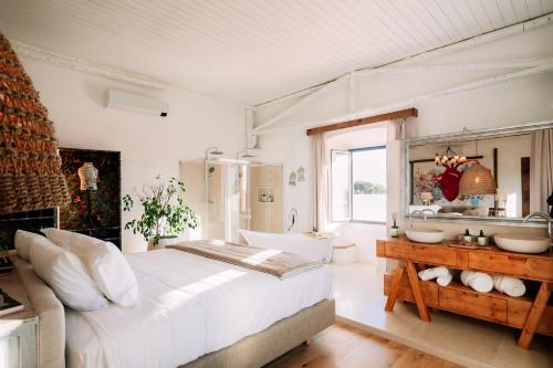 a bedroom with a large white bed and a bathroom at Herdade dos Moreiros in Arronches