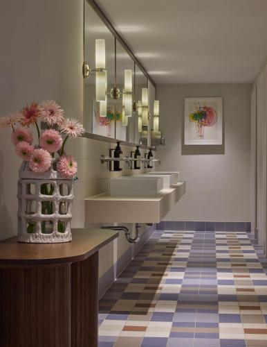 a bathroom with a sink and a mirror and flowers at Miiro Spittelberg NEW OPENING in Vienna