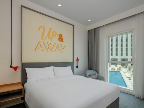 a bedroom with a white bed and a large window at Rove At The Park in Dubai