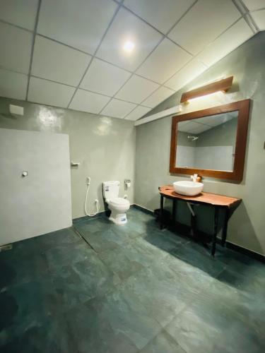 a bathroom with a toilet and a sink and a mirror at Villu Trails Wilpattu in Wilpattu