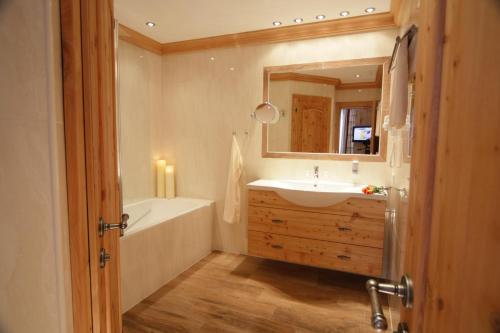 W łazience znajduje się wanna, umywalka i lustro. w obiekcie Hotel Ritterhof w mieście Ellmau